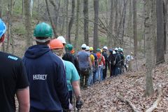 About thirty volunteers in hardhats walking single file along trail